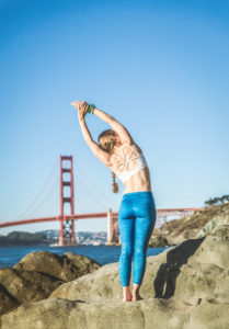 Woman training yoga on the beach at sunset